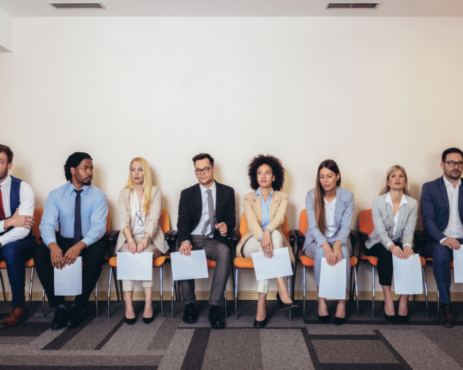 A group of job applicants sits in a row, dressed professionally and holding resumes, waiting for interviews